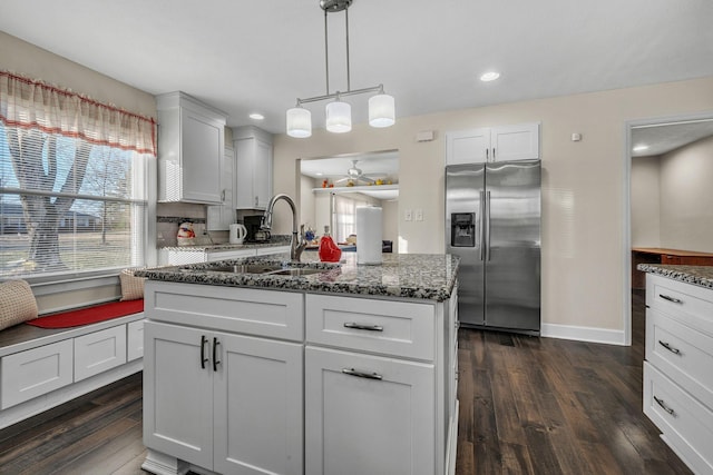 kitchen featuring white cabinetry, sink, stainless steel fridge with ice dispenser, dark wood-type flooring, and a center island with sink