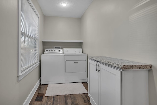 clothes washing area featuring dark hardwood / wood-style flooring, a textured ceiling, cabinets, and washing machine and clothes dryer