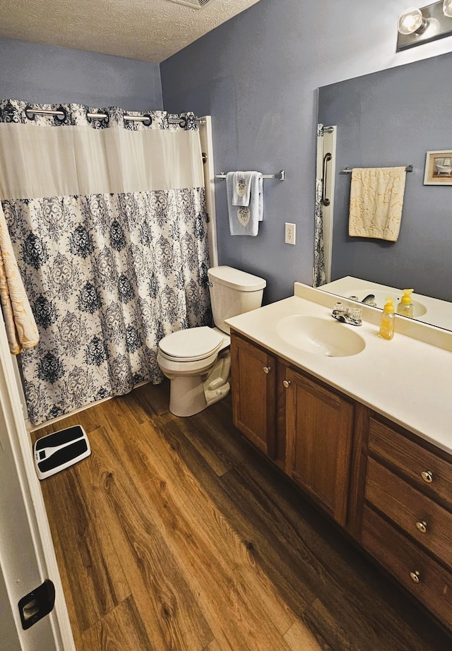 bathroom featuring toilet, vanity, a textured ceiling, and wood finished floors