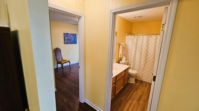 full bathroom with baseboards, visible vents, toilet, wood finished floors, and vanity