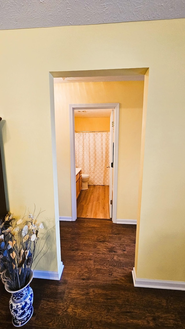 corridor with dark wood finished floors and baseboards