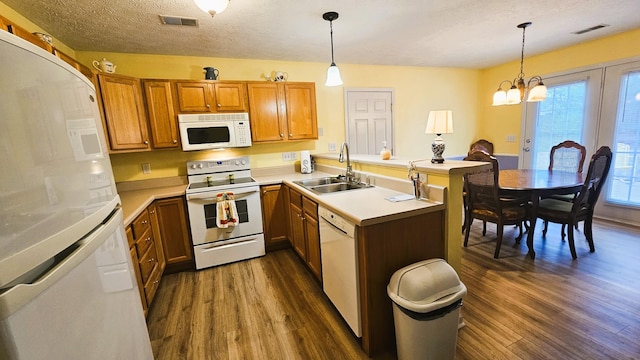 kitchen with hanging light fixtures, sink, white appliances, and dark hardwood / wood-style floors