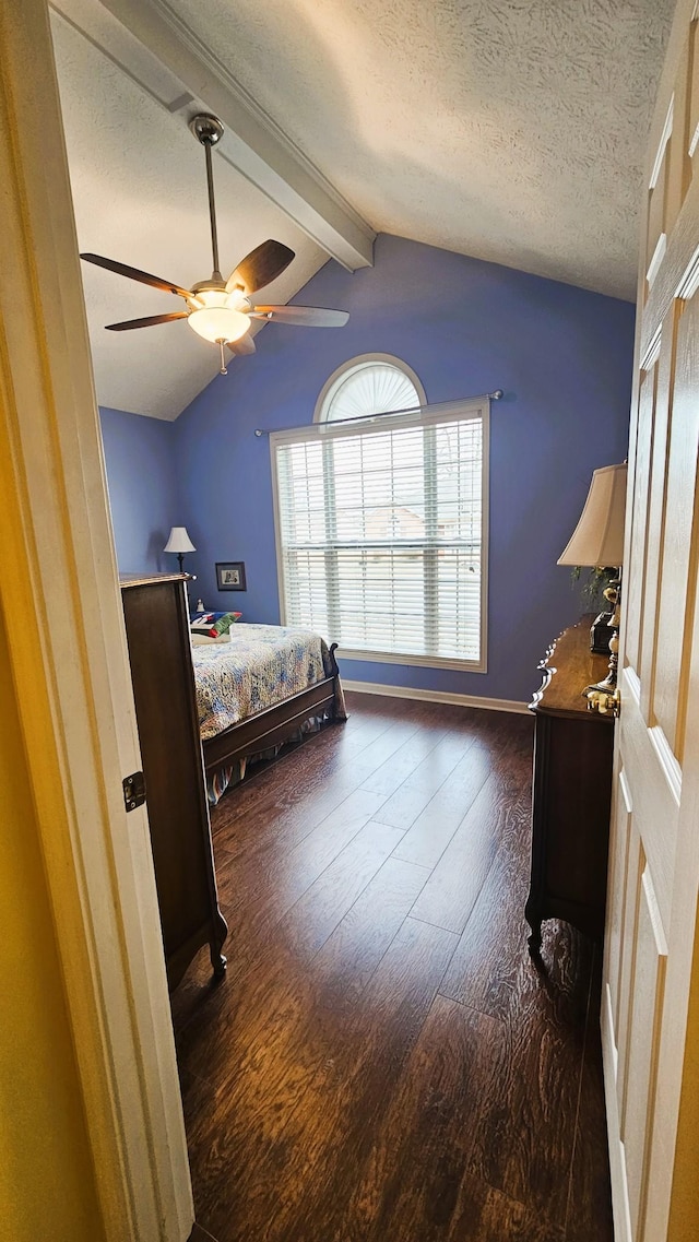 bedroom featuring dark wood-style floors, vaulted ceiling with beams, a textured ceiling, and ceiling fan