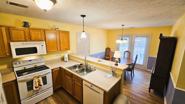 kitchen featuring a peninsula, white appliances, hanging light fixtures, and light countertops