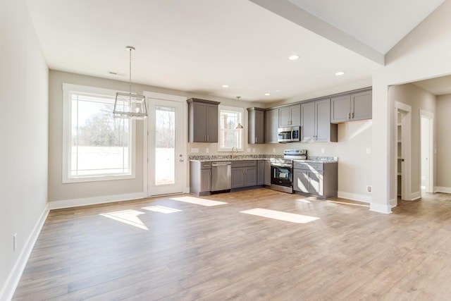 kitchen with stainless steel appliances, gray cabinets, pendant lighting, and light hardwood / wood-style flooring