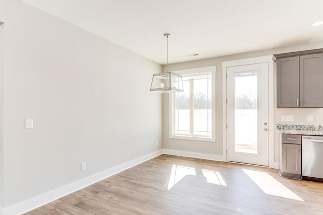 unfurnished dining area featuring an inviting chandelier and light hardwood / wood-style flooring