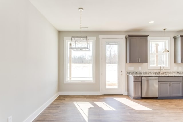 kitchen featuring gray cabinetry, stainless steel dishwasher, light hardwood / wood-style floors, and decorative light fixtures