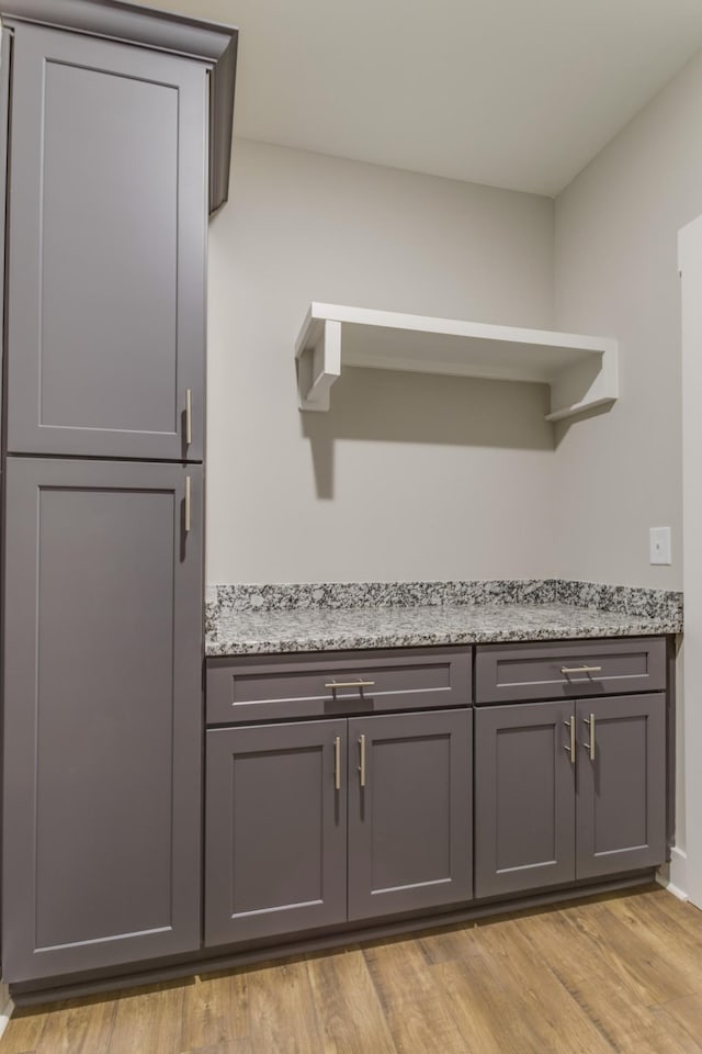 interior space with gray cabinets, light stone countertops, and light hardwood / wood-style floors