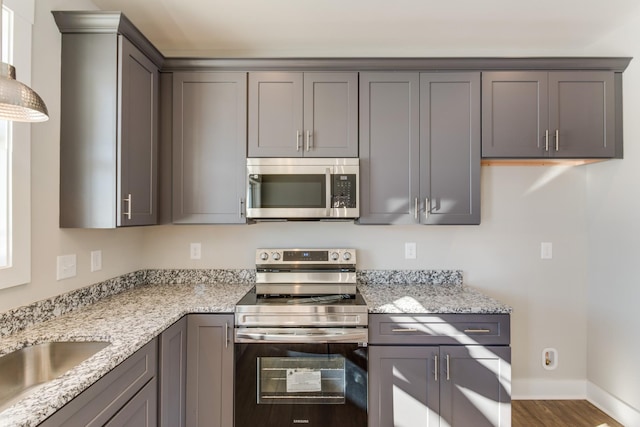 kitchen featuring light stone counters, hardwood / wood-style flooring, gray cabinets, and stainless steel appliances