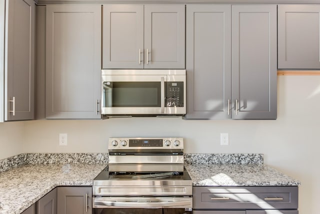 kitchen featuring stainless steel appliances, gray cabinetry, and light stone counters