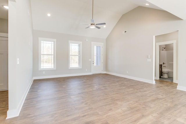 unfurnished living room with high vaulted ceiling, ceiling fan, and light wood-type flooring