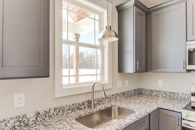 kitchen with stainless steel appliances, sink, light stone counters, and gray cabinets