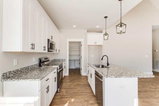 kitchen with appliances with stainless steel finishes, decorative light fixtures, sink, white cabinets, and a kitchen island with sink