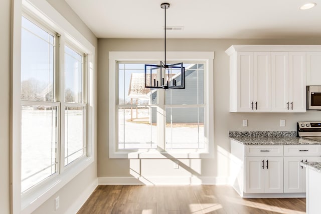 unfurnished dining area with a healthy amount of sunlight, a notable chandelier, and light hardwood / wood-style floors