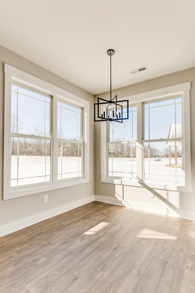 unfurnished dining area featuring an inviting chandelier and hardwood / wood-style floors