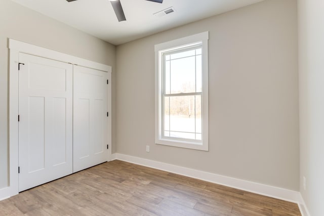 unfurnished bedroom featuring ceiling fan, light hardwood / wood-style floors, and a closet