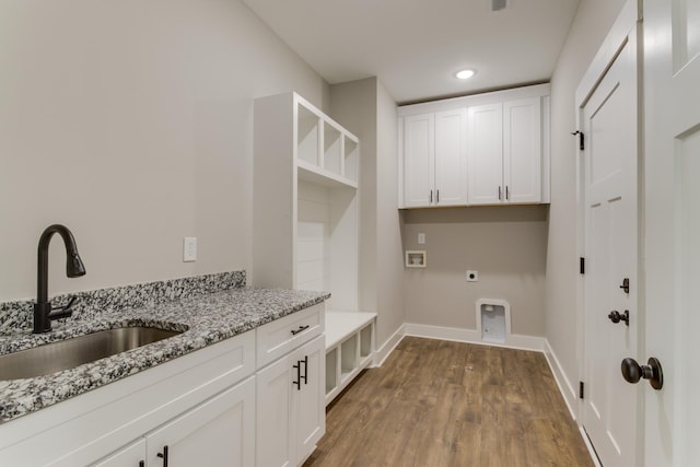 washroom with wood-type flooring, sink, cabinets, hookup for a washing machine, and electric dryer hookup