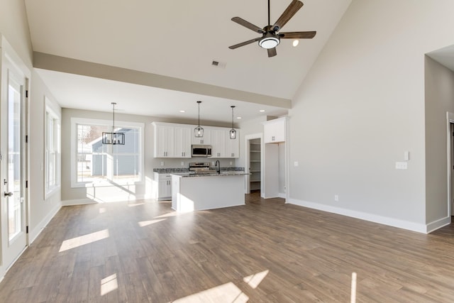 unfurnished living room with ceiling fan with notable chandelier, high vaulted ceiling, sink, and light hardwood / wood-style floors