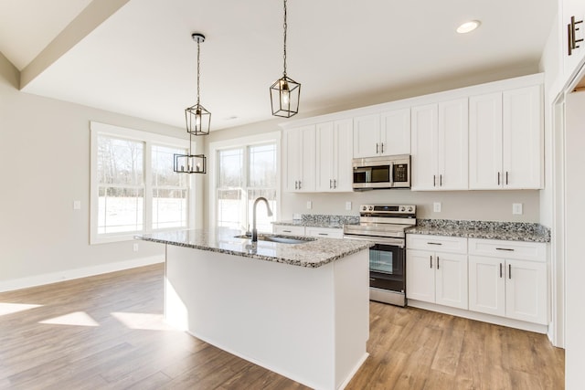 kitchen featuring hanging light fixtures, white cabinetry, appliances with stainless steel finishes, and sink