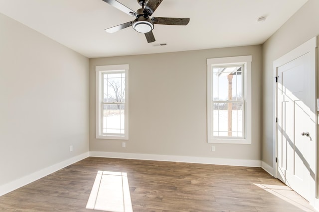 empty room featuring plenty of natural light, ceiling fan, and light hardwood / wood-style flooring