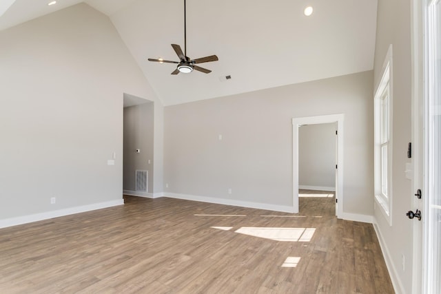 empty room featuring ceiling fan, high vaulted ceiling, and light wood-type flooring