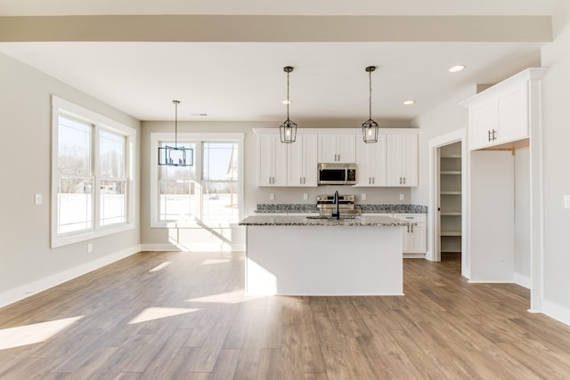 kitchen featuring white cabinetry, a center island with sink, dark stone counters, and appliances with stainless steel finishes