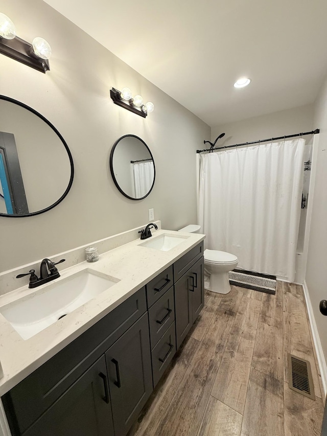 bathroom with hardwood / wood-style flooring, vanity, walk in shower, and toilet