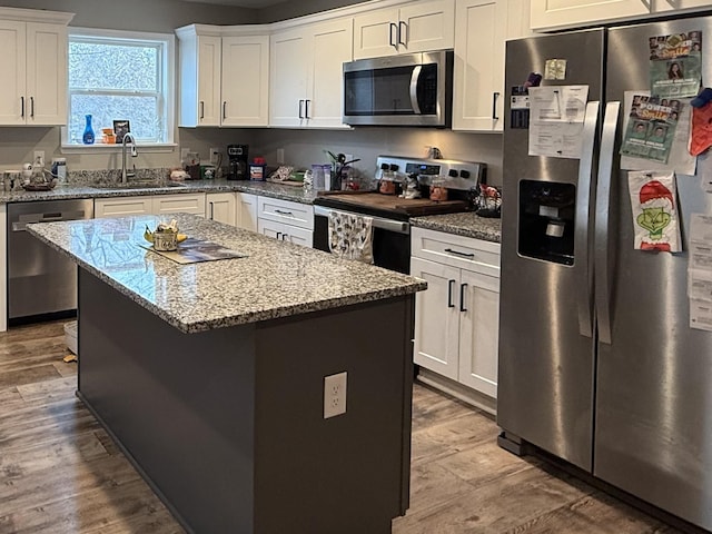 kitchen featuring a kitchen island, white cabinetry, appliances with stainless steel finishes, and sink