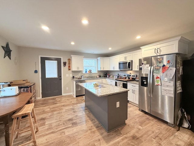 kitchen with white cabinetry, light stone countertops, a center island, and appliances with stainless steel finishes