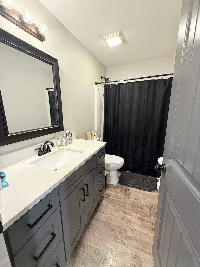 bathroom with walk in shower, vanity, toilet, and hardwood / wood-style floors