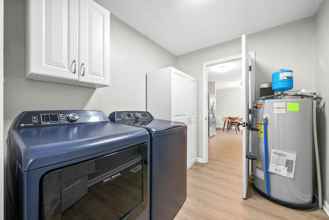 clothes washing area with cabinets, light hardwood / wood-style floors, washing machine and dryer, and water heater