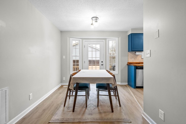 dining room featuring a textured ceiling and light wood-type flooring