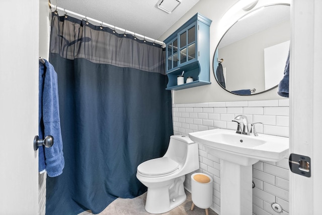 bathroom with walk in shower, toilet, and tile walls