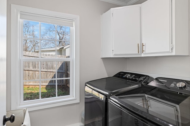 clothes washing area with cabinets and washer and clothes dryer