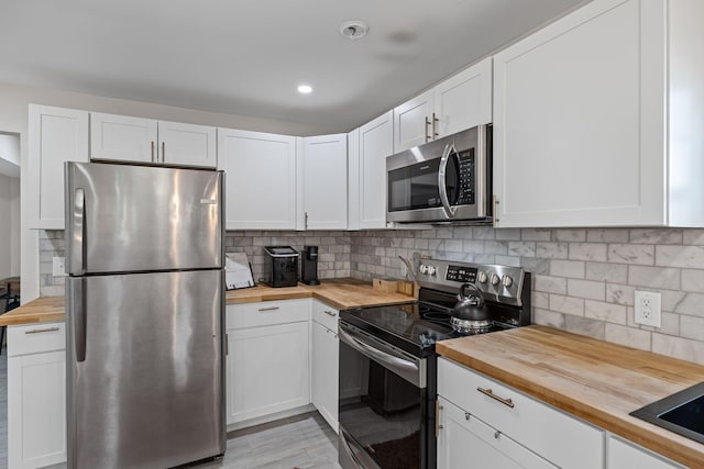 kitchen with backsplash, appliances with stainless steel finishes, wooden counters, and white cabinets