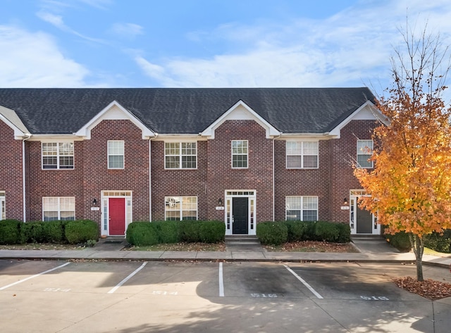 view of front of house with brick siding and roof with shingles