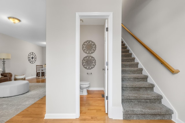 staircase featuring baseboards and wood finished floors