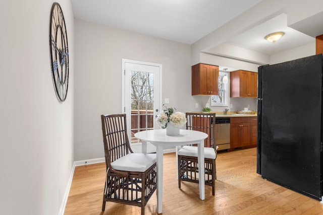 dining space featuring a healthy amount of sunlight, light wood-style flooring, and baseboards