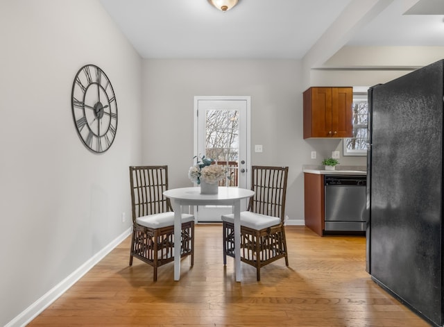 dining room featuring light wood finished floors, baseboards, and a wealth of natural light