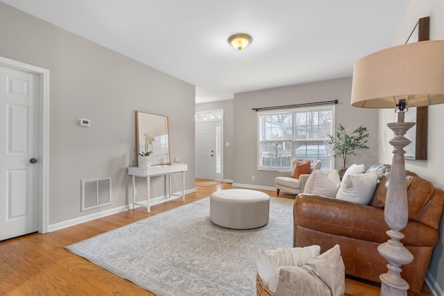 living area featuring light wood-style flooring, visible vents, and baseboards