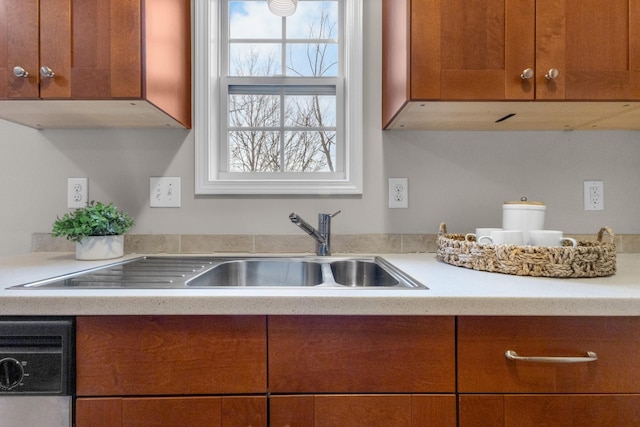 kitchen with brown cabinetry, light countertops, and a sink