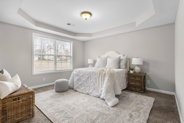 carpeted bedroom with baseboards, visible vents, and a raised ceiling