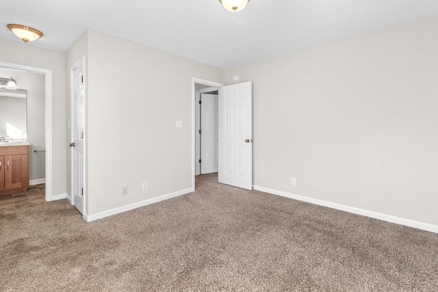 unfurnished bedroom featuring carpet floors, baseboards, and ensuite bathroom