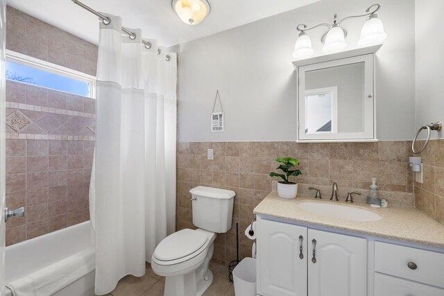 full bathroom featuring tile walls, vanity, tile patterned floors, toilet, and shower / bath combo with shower curtain