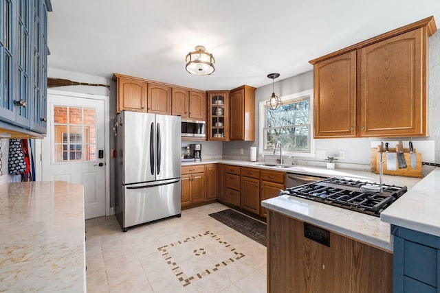 kitchen with sink, stainless steel appliances, light stone countertops, light tile patterned flooring, and decorative light fixtures