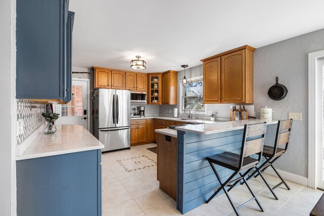 kitchen featuring a breakfast bar, pendant lighting, sink, kitchen peninsula, and stainless steel appliances