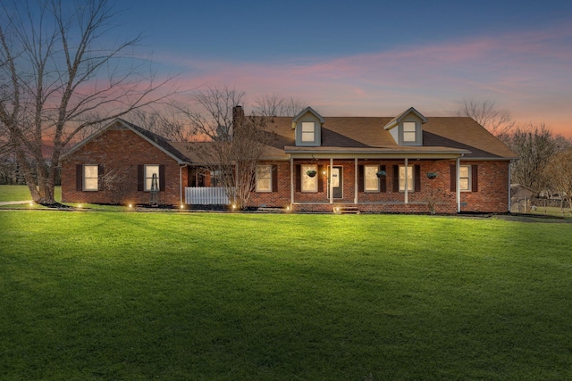 cape cod home with a porch and a lawn