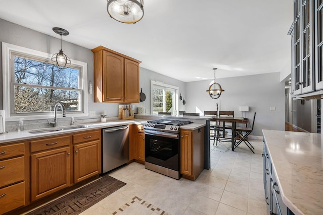 kitchen featuring sink, light tile patterned flooring, hanging light fixtures, and appliances with stainless steel finishes