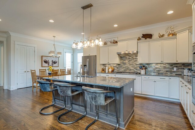 kitchen featuring hanging light fixtures, an island with sink, appliances with stainless steel finishes, and white cabinetry