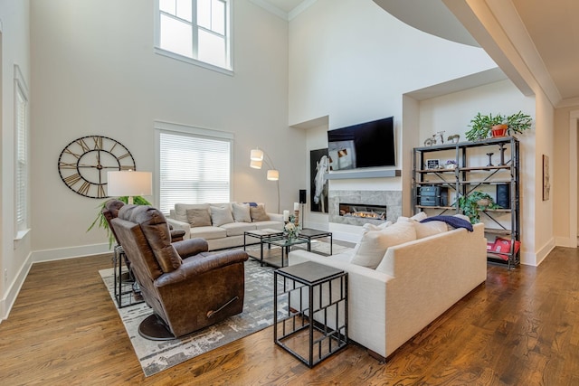 living room featuring a premium fireplace, plenty of natural light, wood-type flooring, and crown molding